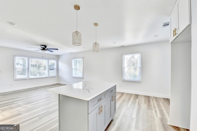 kitchen with pendant lighting, light stone counters, light hardwood / wood-style floors, and white cabinetry