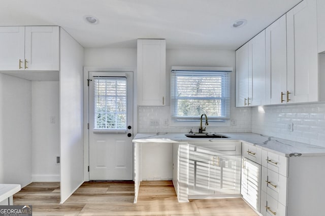 kitchen featuring backsplash, light stone countertops, and white cabinets