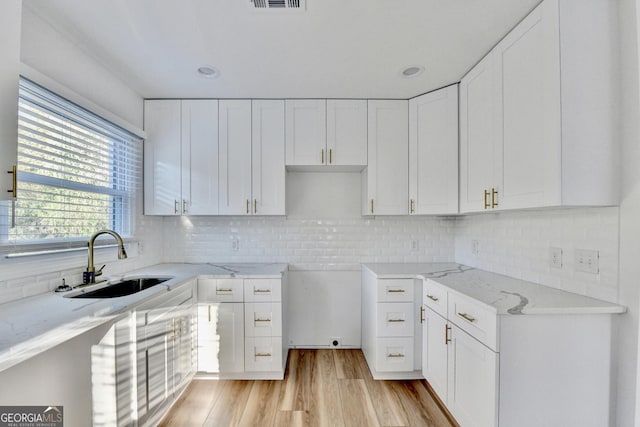 kitchen with white cabinetry, sink, backsplash, and light hardwood / wood-style floors