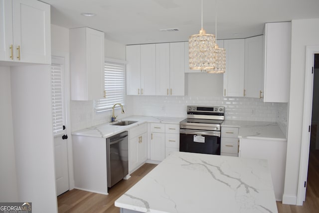 kitchen featuring hanging light fixtures, sink, white cabinets, and stainless steel appliances