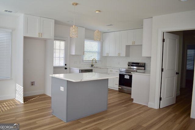 kitchen with a kitchen island, pendant lighting, white cabinetry, sink, and stainless steel range with electric cooktop