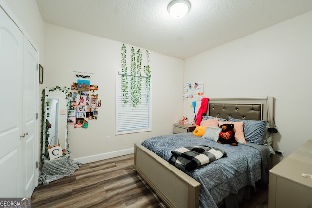 bedroom featuring dark hardwood / wood-style floors, a textured ceiling, and a closet