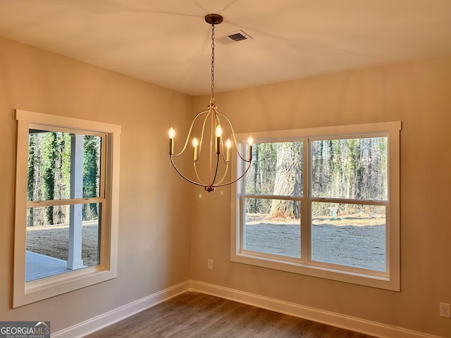 unfurnished dining area featuring plenty of natural light, hardwood / wood-style floors, and a notable chandelier