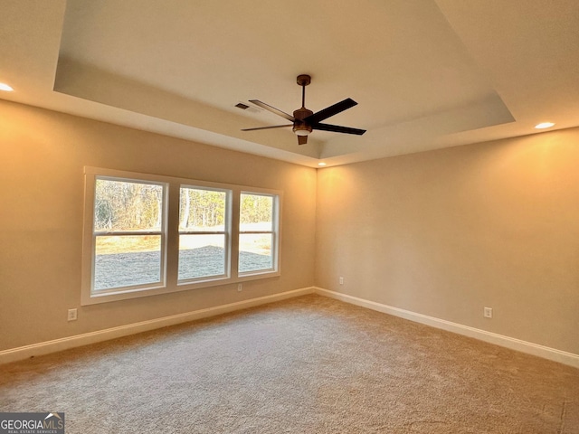 unfurnished room with a raised ceiling, carpet floors, and ceiling fan