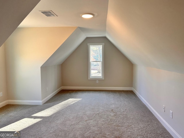 bonus room with vaulted ceiling and light colored carpet