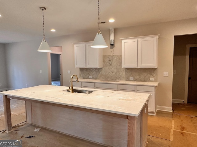 kitchen featuring backsplash, white cabinetry, sink, and a kitchen island with sink