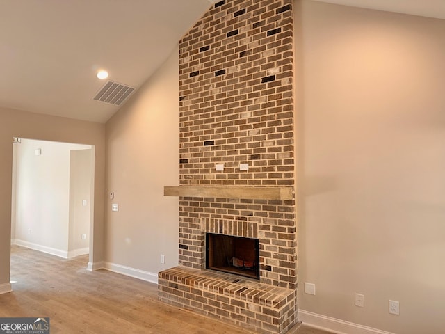 unfurnished living room featuring a brick fireplace, wood-type flooring, and high vaulted ceiling