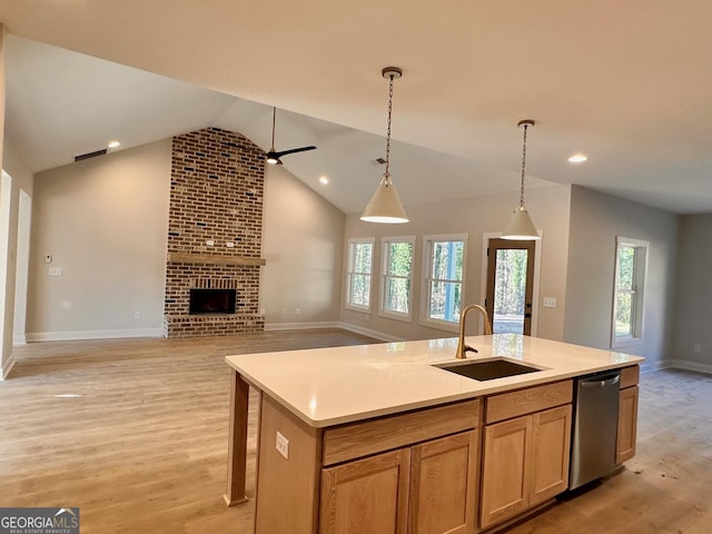 kitchen featuring a fireplace, decorative light fixtures, dishwasher, sink, and a center island with sink