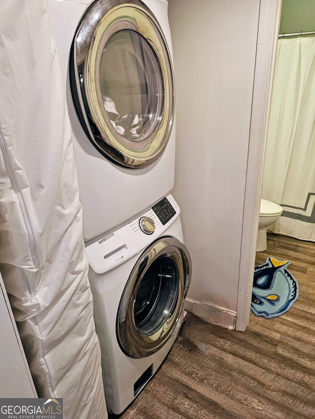 laundry room with stacked washer / dryer and dark wood-type flooring