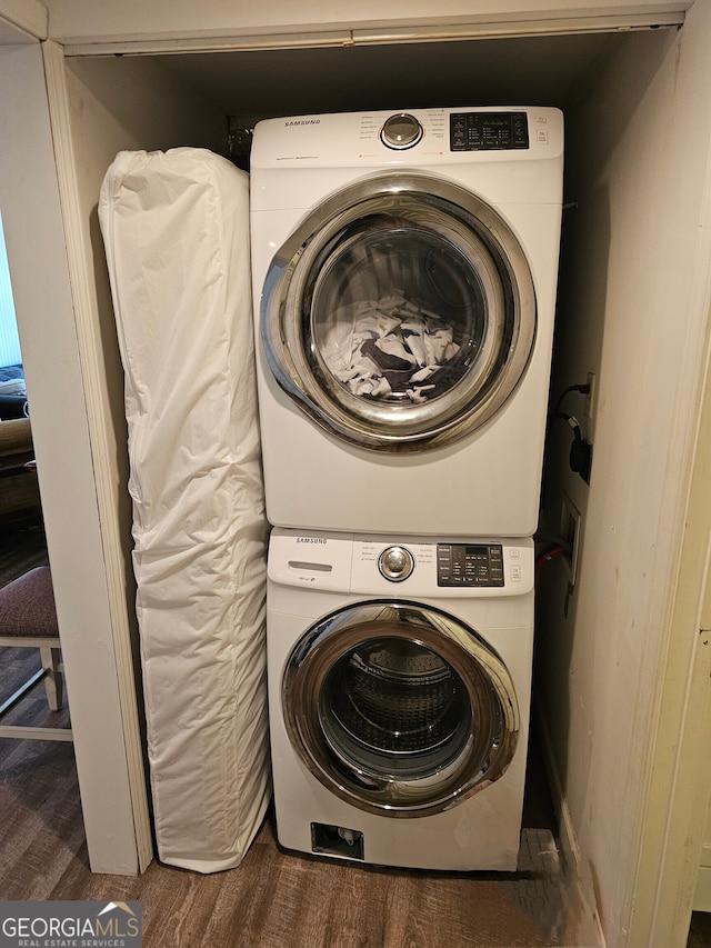 laundry area with stacked washer and dryer and dark wood-type flooring