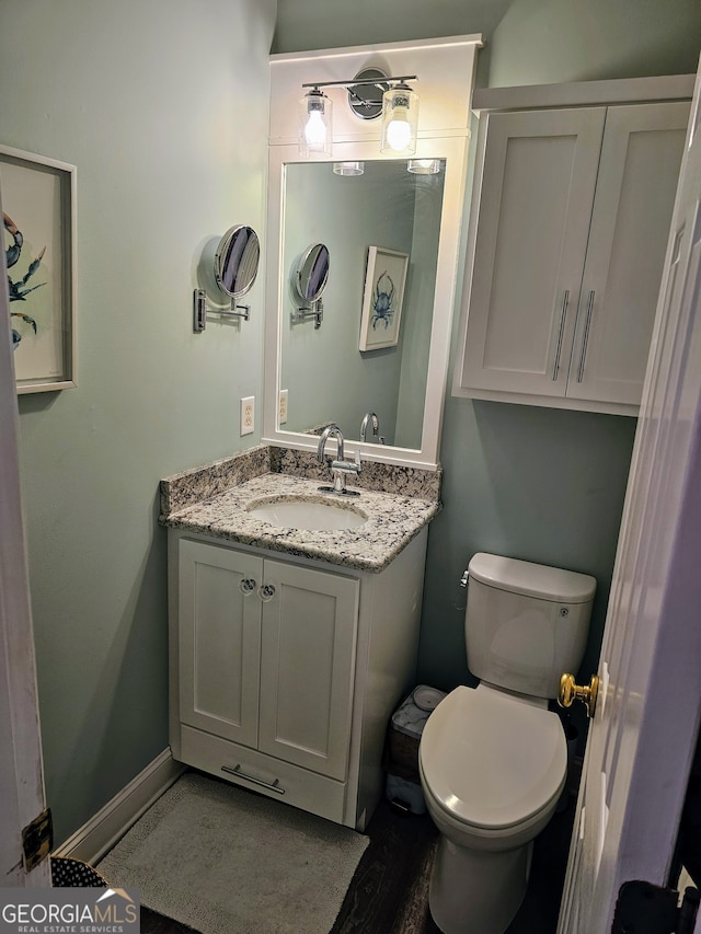 bathroom with wood-type flooring, vanity, and toilet