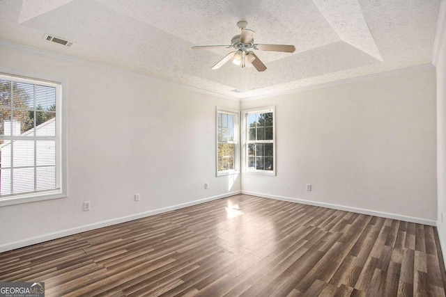 spare room with a tray ceiling, a wealth of natural light, crown molding, and dark hardwood / wood-style floors