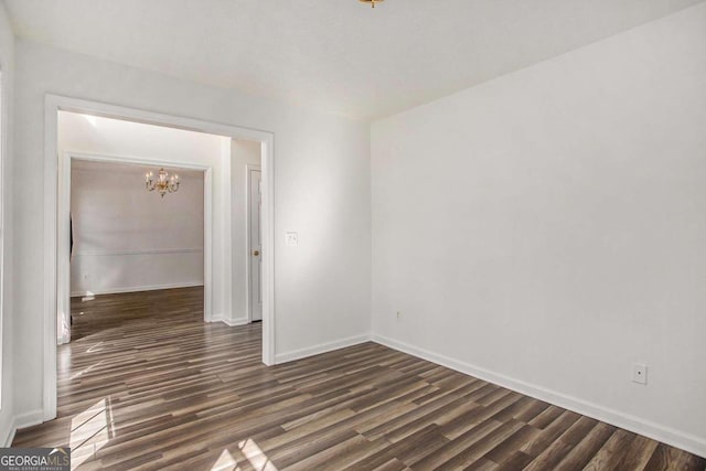 unfurnished room featuring a chandelier and dark hardwood / wood-style flooring