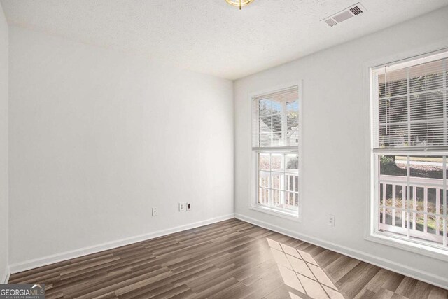 spare room featuring a textured ceiling and dark hardwood / wood-style floors