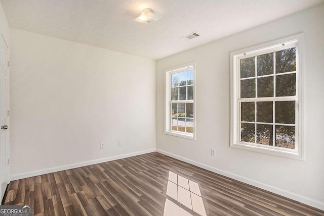 empty room with dark hardwood / wood-style flooring and a textured ceiling