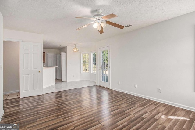 unfurnished living room featuring a textured ceiling, ceiling fan, and dark wood-type flooring