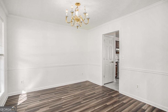 empty room with a textured ceiling, crown molding, dark hardwood / wood-style floors, and an inviting chandelier