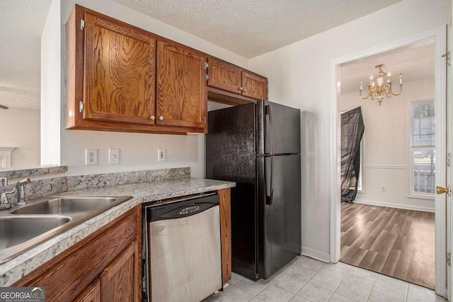 kitchen with dishwasher, an inviting chandelier, black refrigerator, light hardwood / wood-style flooring, and a textured ceiling