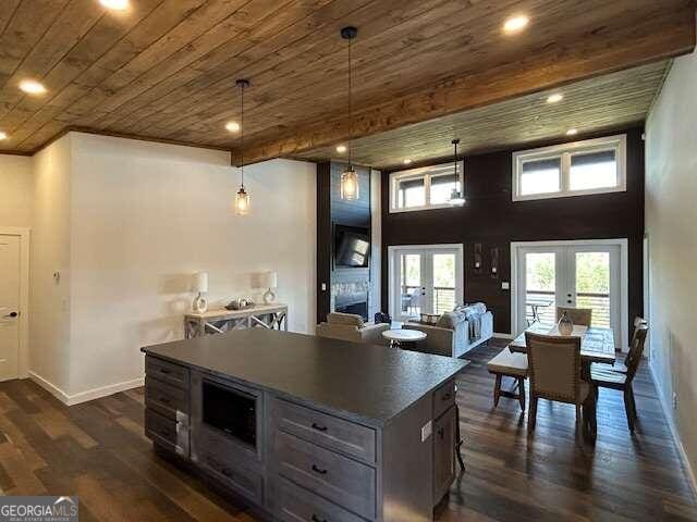 kitchen with pendant lighting, dark hardwood / wood-style floors, a kitchen island, wooden ceiling, and french doors