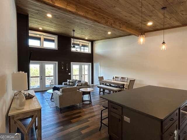 living room featuring dark hardwood / wood-style floors, wooden ceiling, french doors, and a towering ceiling