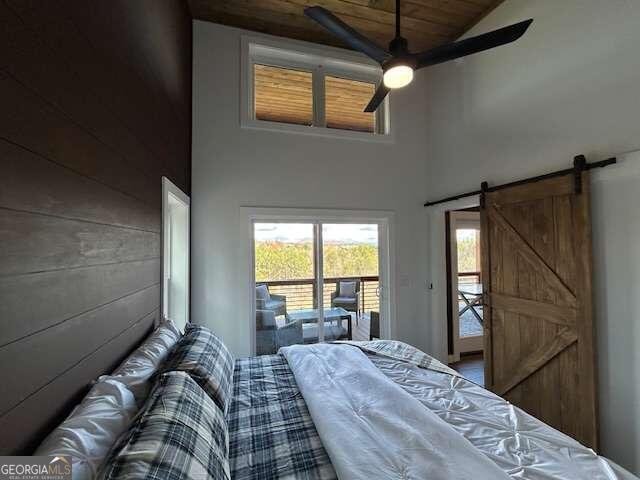 bedroom with high vaulted ceiling, access to outside, ceiling fan, wood ceiling, and a barn door