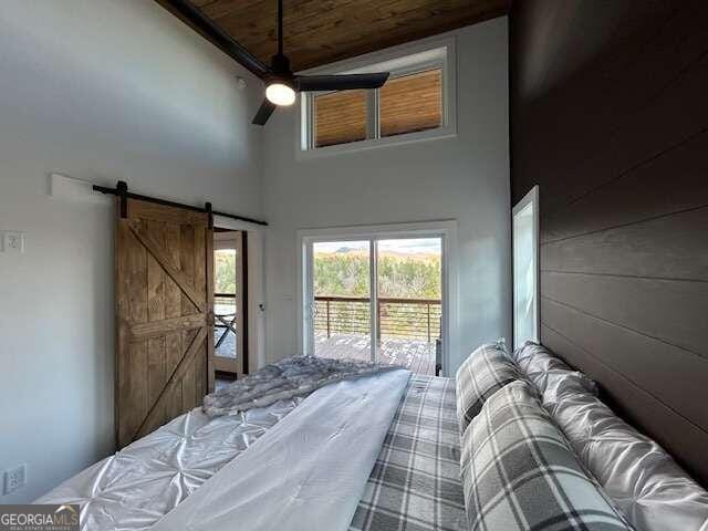 bedroom featuring a barn door, a towering ceiling, and ceiling fan