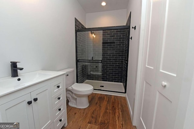 bathroom with walk in shower, hardwood / wood-style floors, vanity, and toilet