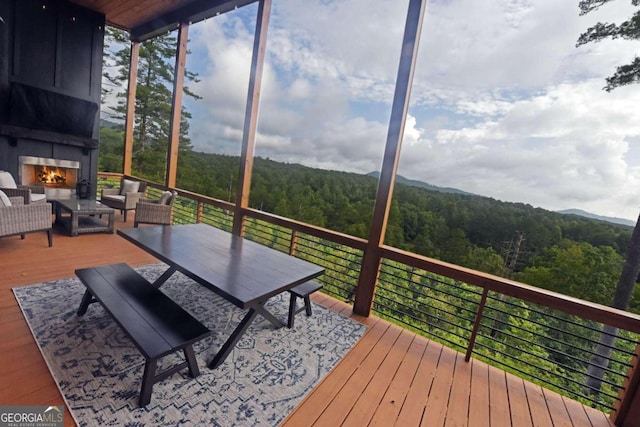 wooden terrace with an outdoor living space with a fireplace