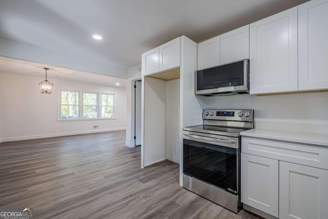 kitchen featuring white cabinetry, a notable chandelier, pendant lighting, light hardwood / wood-style floors, and appliances with stainless steel finishes