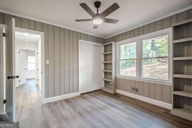 unfurnished bedroom featuring crown molding, ceiling fan, a closet, and light hardwood / wood-style floors