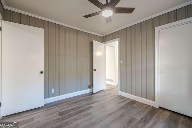 unfurnished bedroom featuring ceiling fan, crown molding, and light hardwood / wood-style flooring