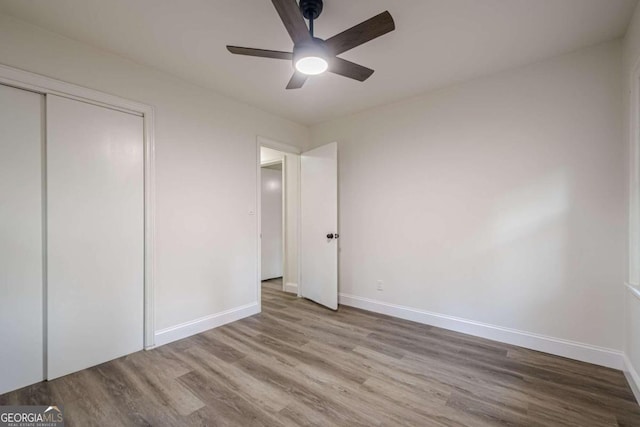 unfurnished bedroom featuring ceiling fan, light wood-type flooring, and a closet