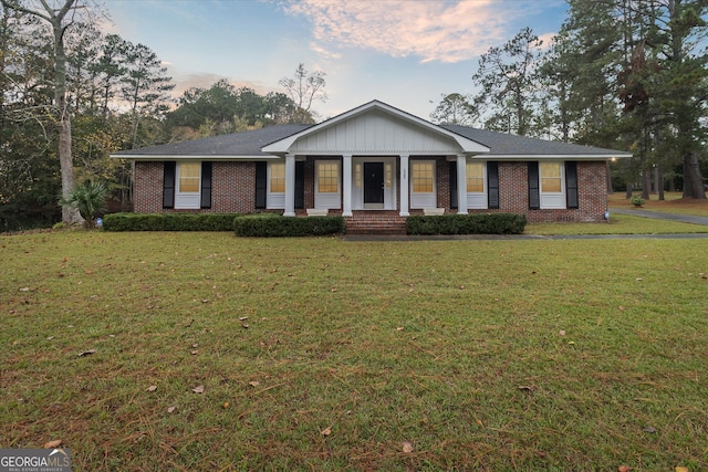 ranch-style home featuring a lawn and covered porch