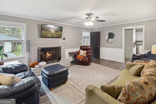 living room featuring hardwood / wood-style floors, a brick fireplace, ceiling fan, and ornamental molding