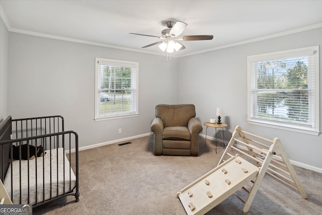 carpeted bedroom featuring ceiling fan, crown molding, and a nursery area