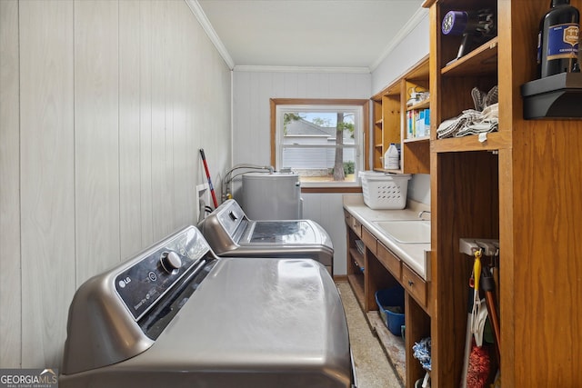 clothes washing area featuring sink, crown molding, wooden walls, carpet flooring, and washing machine and clothes dryer