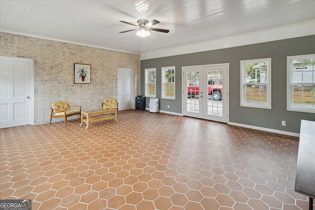 unfurnished room featuring french doors, ceiling fan, crown molding, and brick wall