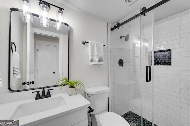 bathroom with a shower with door, vanity, and toilet