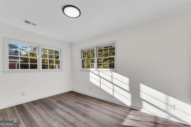 unfurnished room with crown molding, plenty of natural light, and wood-type flooring