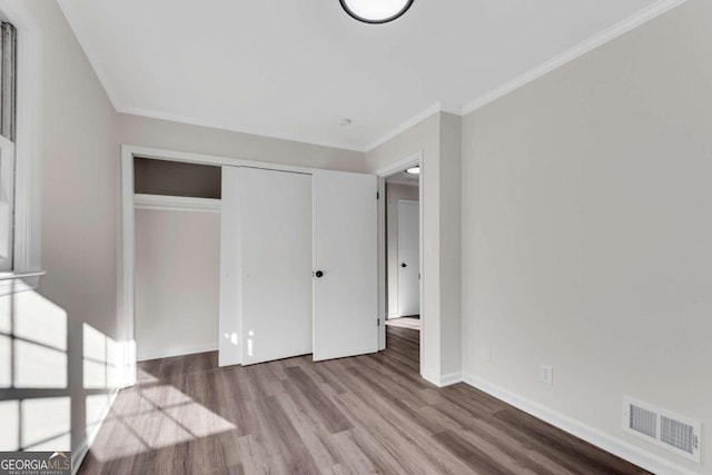 unfurnished bedroom featuring crown molding, a closet, and light hardwood / wood-style floors