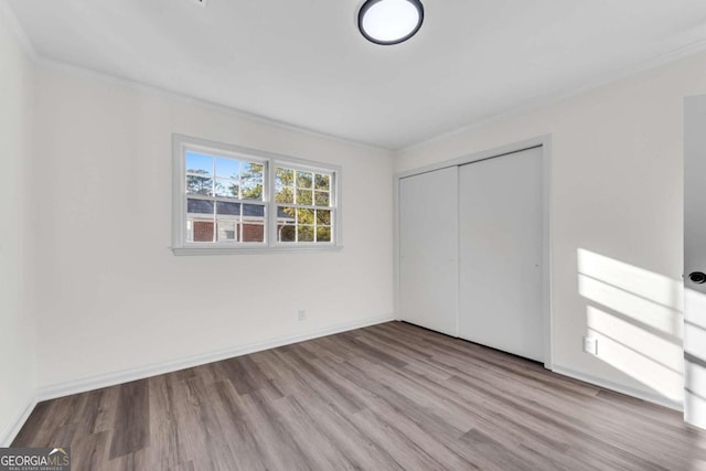 unfurnished bedroom with crown molding, a closet, and light hardwood / wood-style flooring