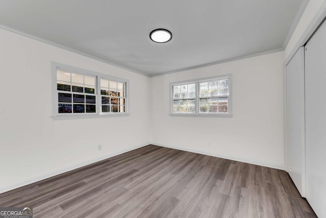 spare room with wood-type flooring, a wealth of natural light, and crown molding