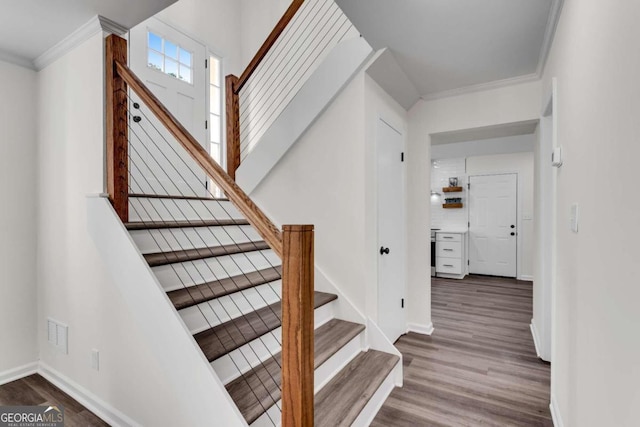 staircase with ornamental molding and hardwood / wood-style flooring