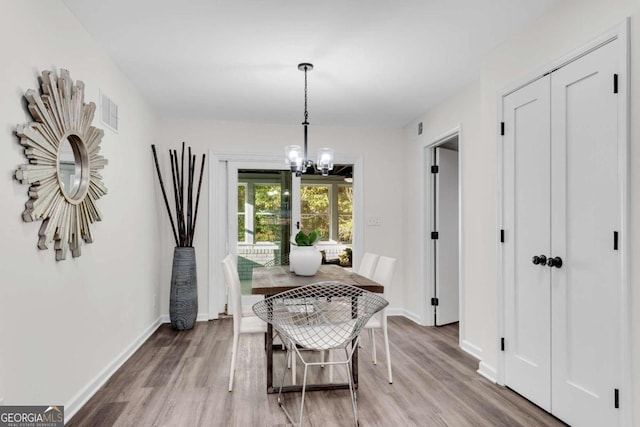 dining space featuring hardwood / wood-style floors and an inviting chandelier