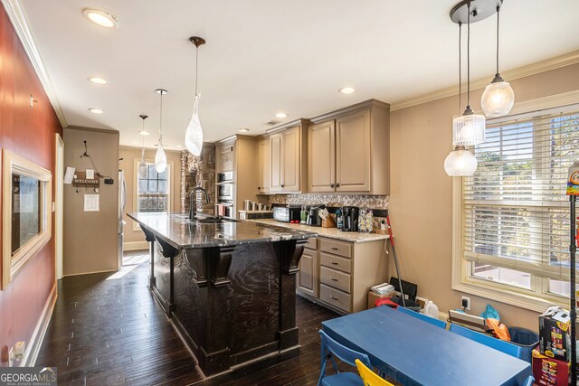 kitchen with decorative light fixtures, an island with sink, and a wealth of natural light