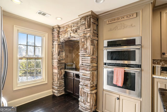 kitchen with appliances with stainless steel finishes, backsplash, ornamental molding, cream cabinets, and dark hardwood / wood-style floors