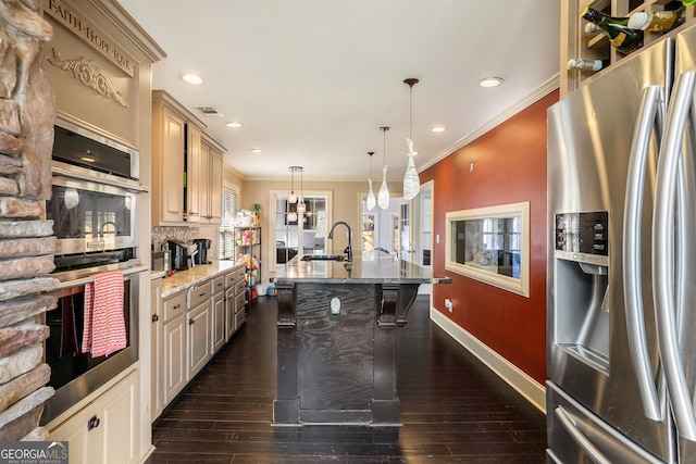 kitchen featuring light stone countertops, dark wood-type flooring, pendant lighting, appliances with stainless steel finishes, and ornamental molding