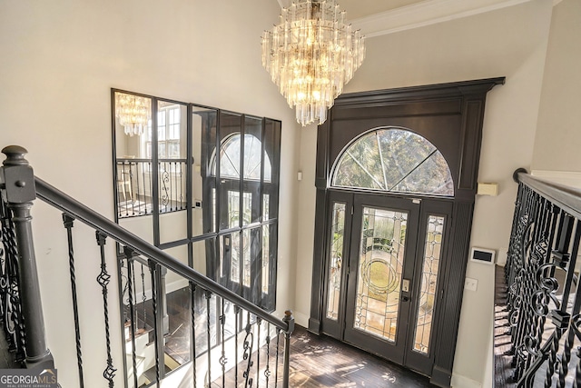 foyer entrance with crown molding, dark hardwood / wood-style floors, and an inviting chandelier