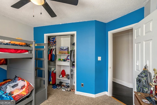 carpeted bedroom featuring ceiling fan and a textured ceiling