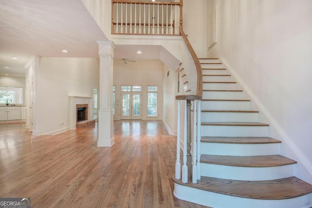 stairway featuring hardwood / wood-style flooring, a towering ceiling, sink, and decorative columns